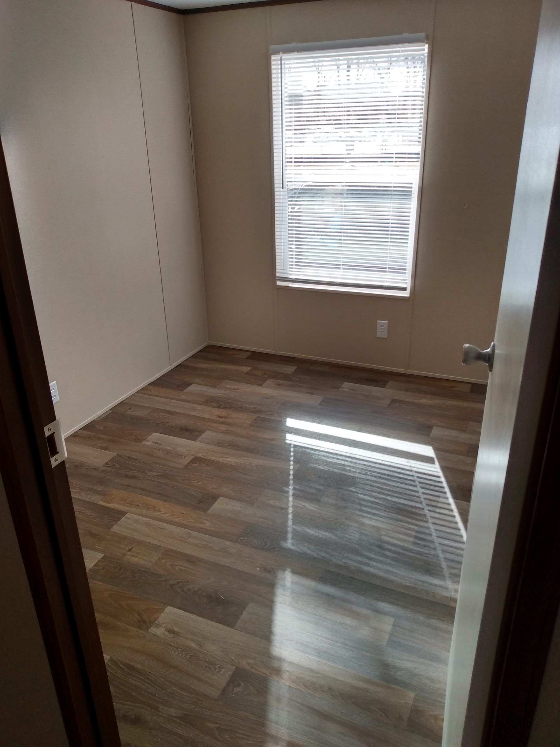 Room with a window, blinds and wood-look flooring