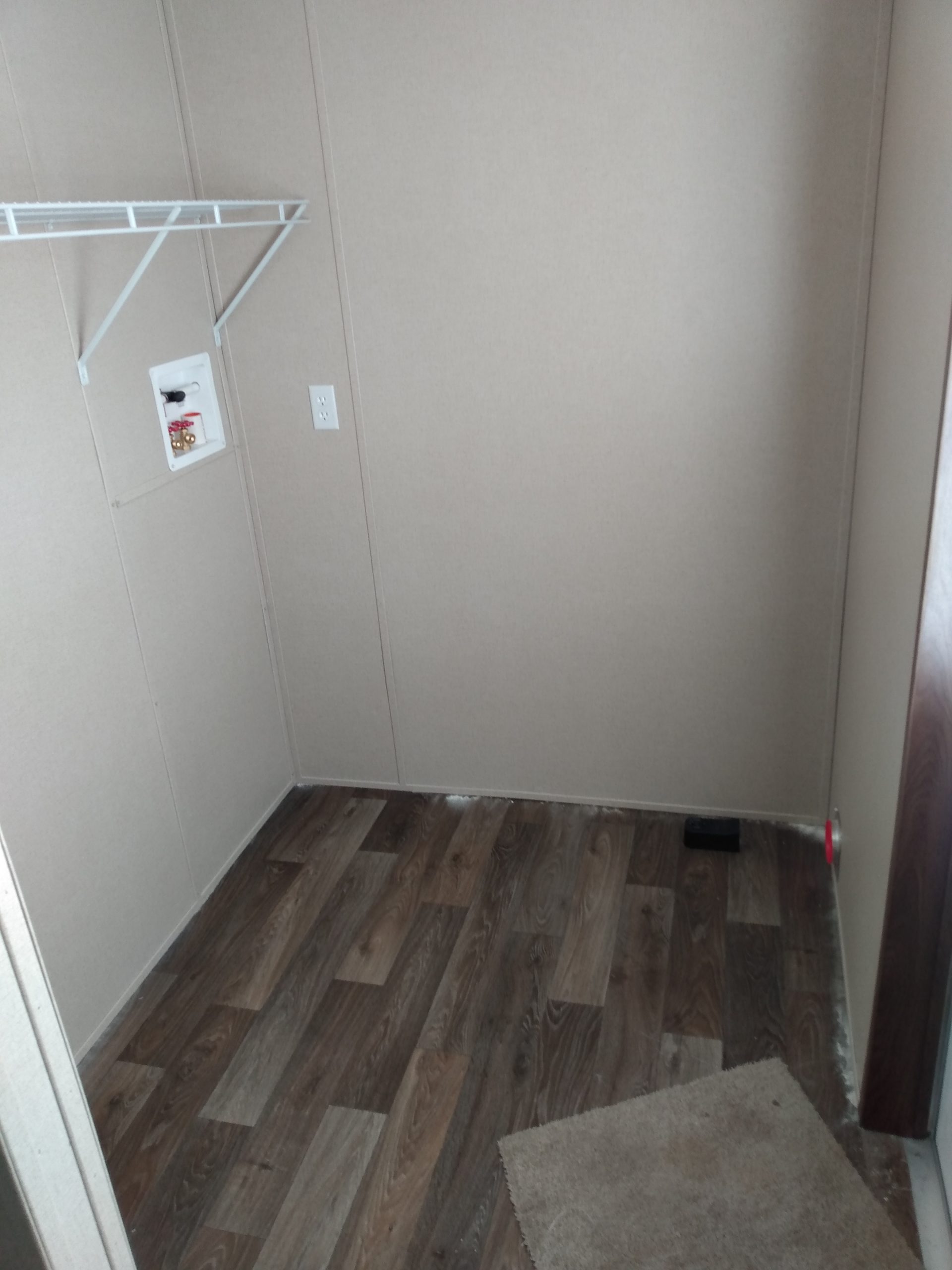 Room with a wire shelf, wall connections and wood-look flooring